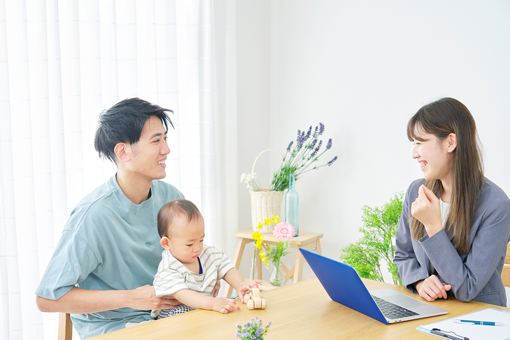 赤ちゃんを抱いた若い夫婦が、話し合っている写真