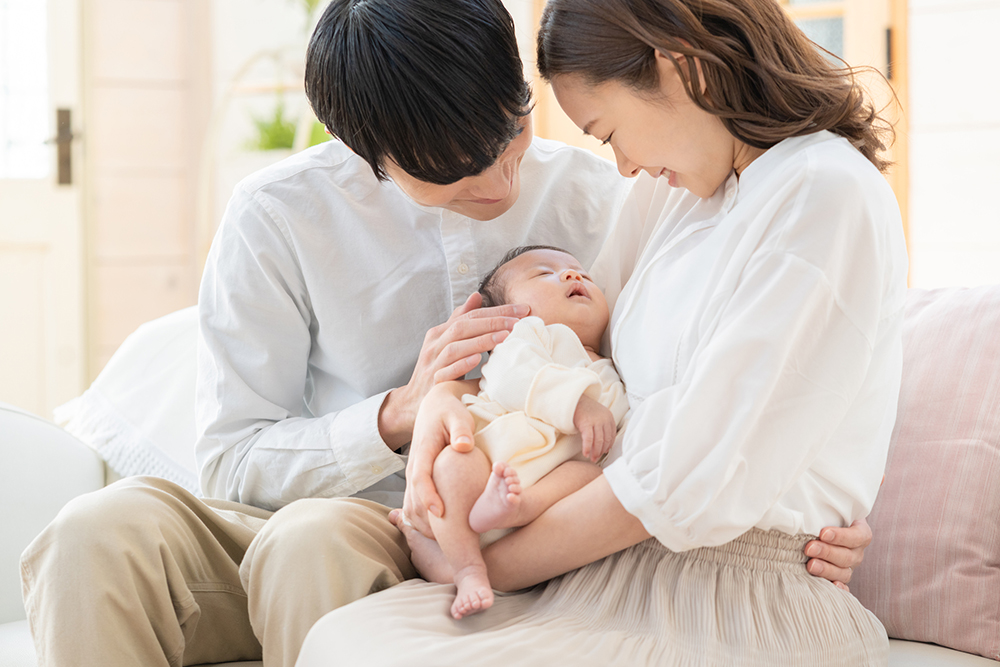 家族に抱っこされて眠る赤ちゃんの写真