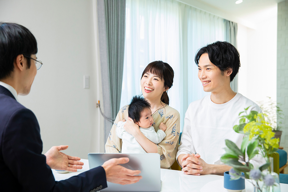 赤ちゃんを抱いたファミリーと営業マンの写真